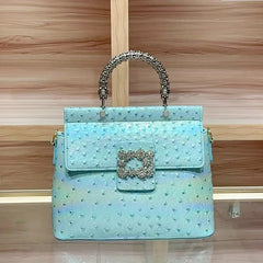 Blue ostrich print textured handbag with a silver jeweled buckle and structured top handle.