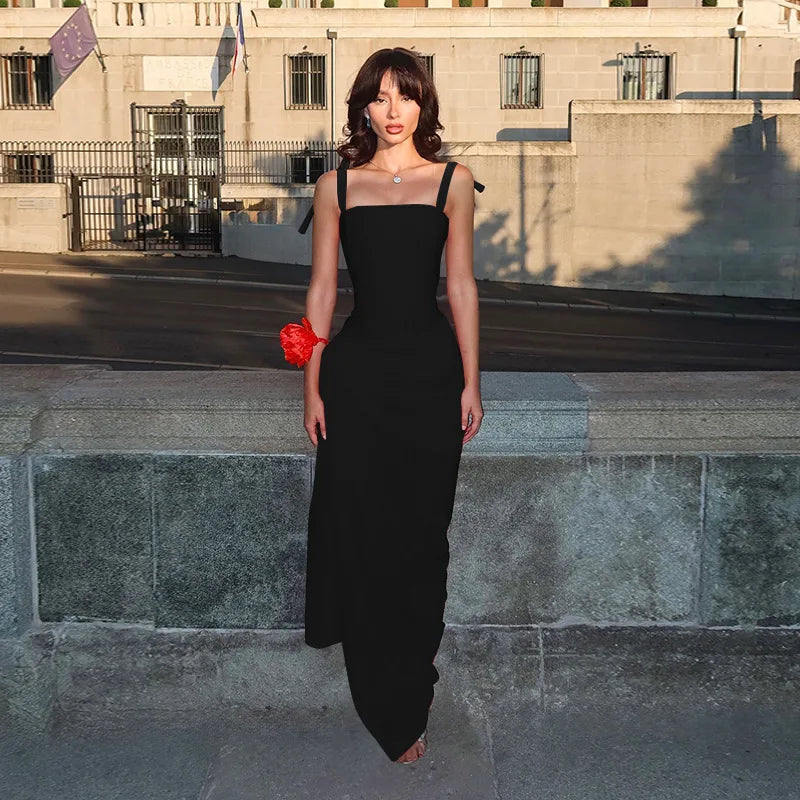 Woman in a black dress standing on stone steps with a building in the background