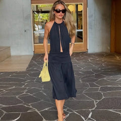 Woman in a navy dress holding a yellow handbag on a stone pavement.