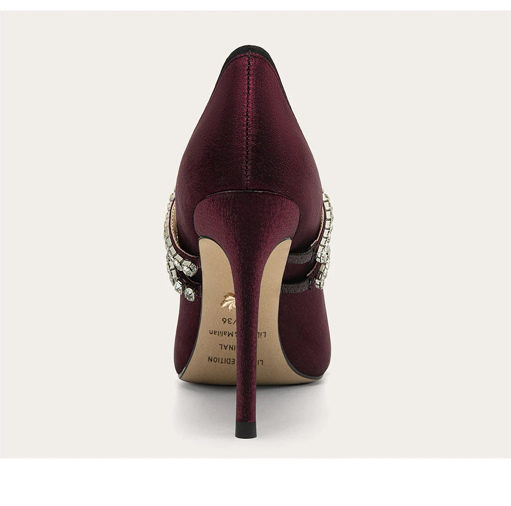 Maroon high-heeled shoe with embellishments on a white background