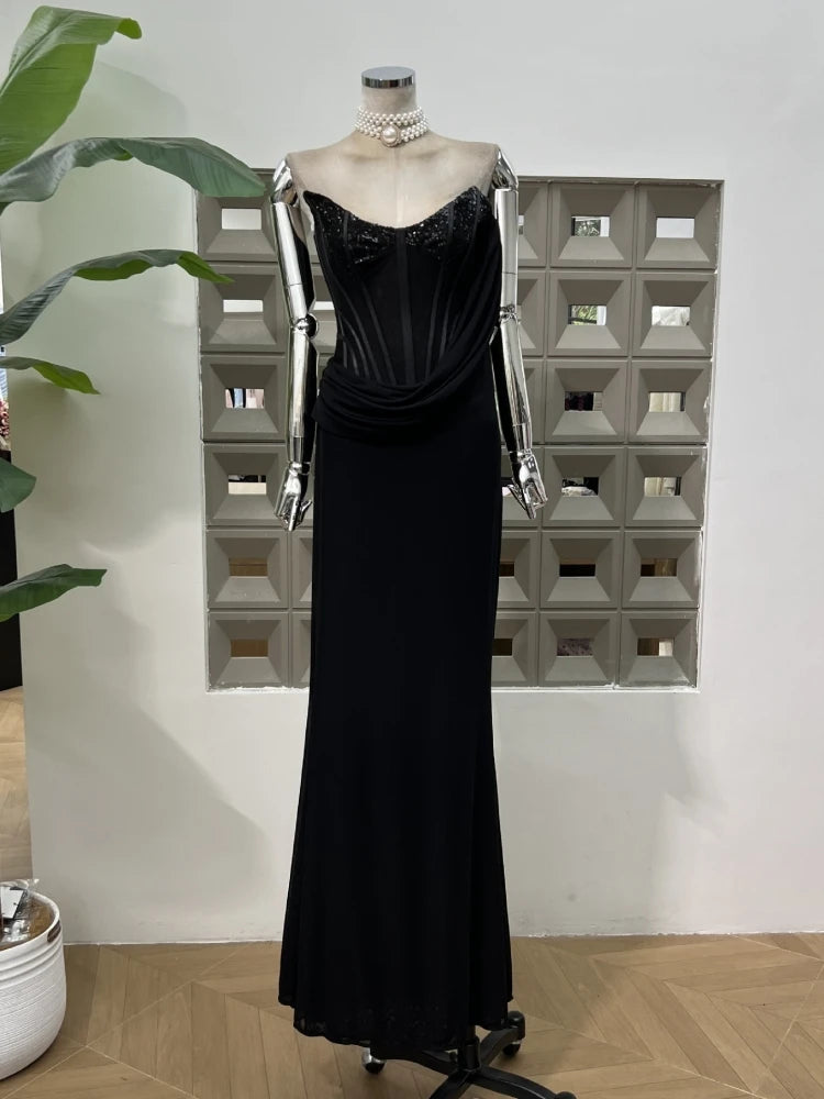 Black evening gown on a mannequin against a white wall with geometric mirror