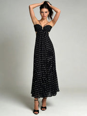 Woman posing in black polka dot maxi dress with strappy detail