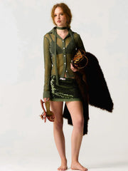Woman wearing a green knitted cardigan and skirt with a black fur stole on a white background