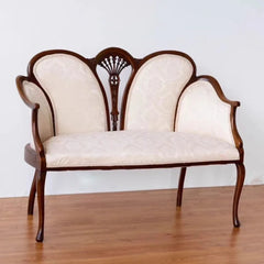 Vintage-style wooden bench with cream upholstery on a wooden floor.