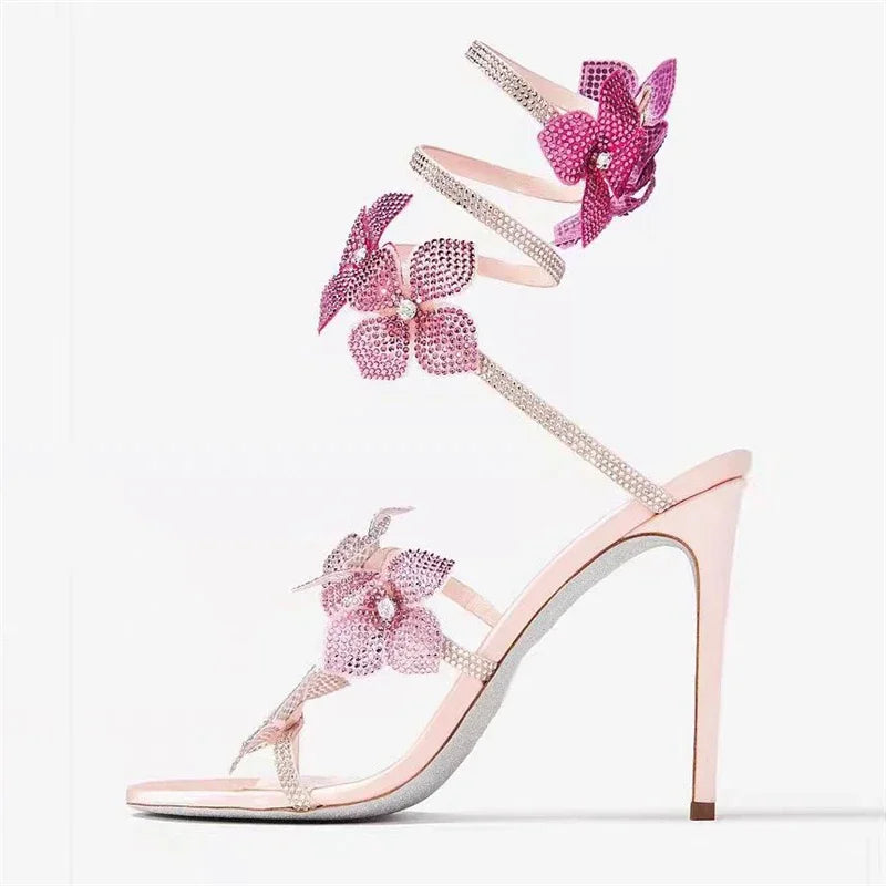 A person wearing pink crystal flower ankle strap stiletto heels