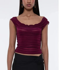 Woman wearing a burgundy top with a plain background