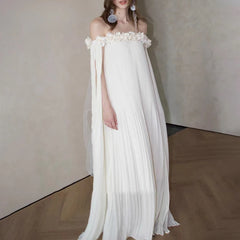 Woman wearing beige off-shoulder maxi dress with floral neckline and floor-length A-line silhouette.