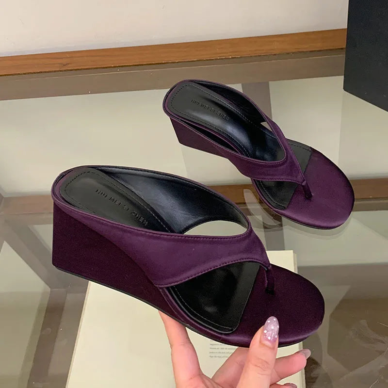 Purple wedge flip flop sandals being held