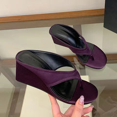 Purple wedge flip flop sandals being held