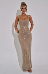 Woman wearing a sparkly gold dress against a plain background