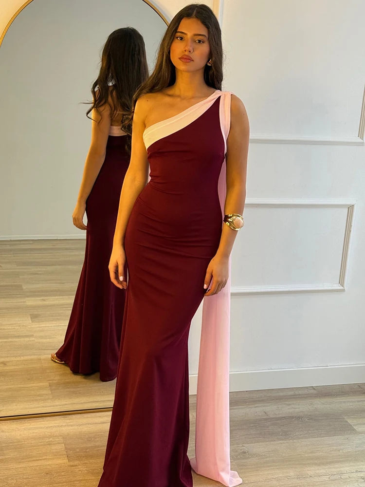 Woman wearing a burgundy and pink one-shoulder dress standing in front of a mirror.