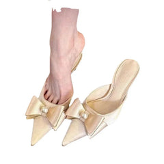  A woman wearing a pair of elegant beige bowknot kitten heels with pointed toes, perfect for formal events. 2