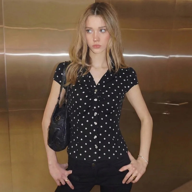 Woman wearing a black polka dot shirt with a black handbag in an elevator.
