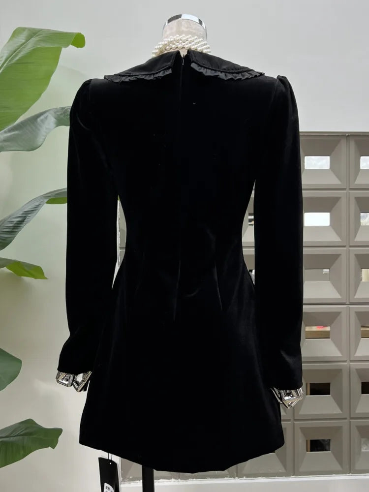 Black dress on a mannequin against a white wall with decorative elements