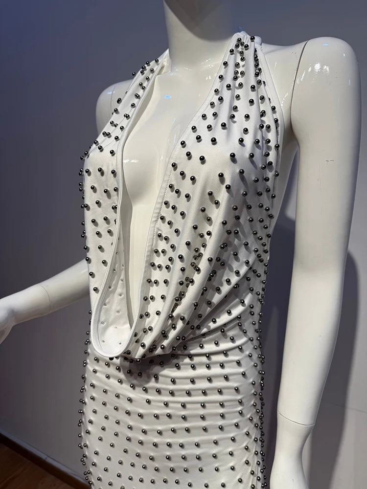 Mannequin wearing a white dress with black bead embellishments against a neutral background
