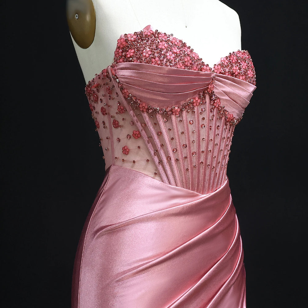 Pink evening gown with intricate beading on a mannequin against a black background