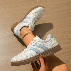 Hand holding floral print lace-up sneakers, showing the sole.