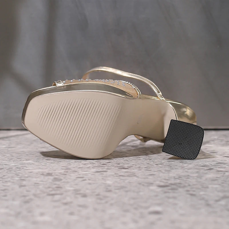 Gold high-heeled shoe with a textured sole on a gray surface
