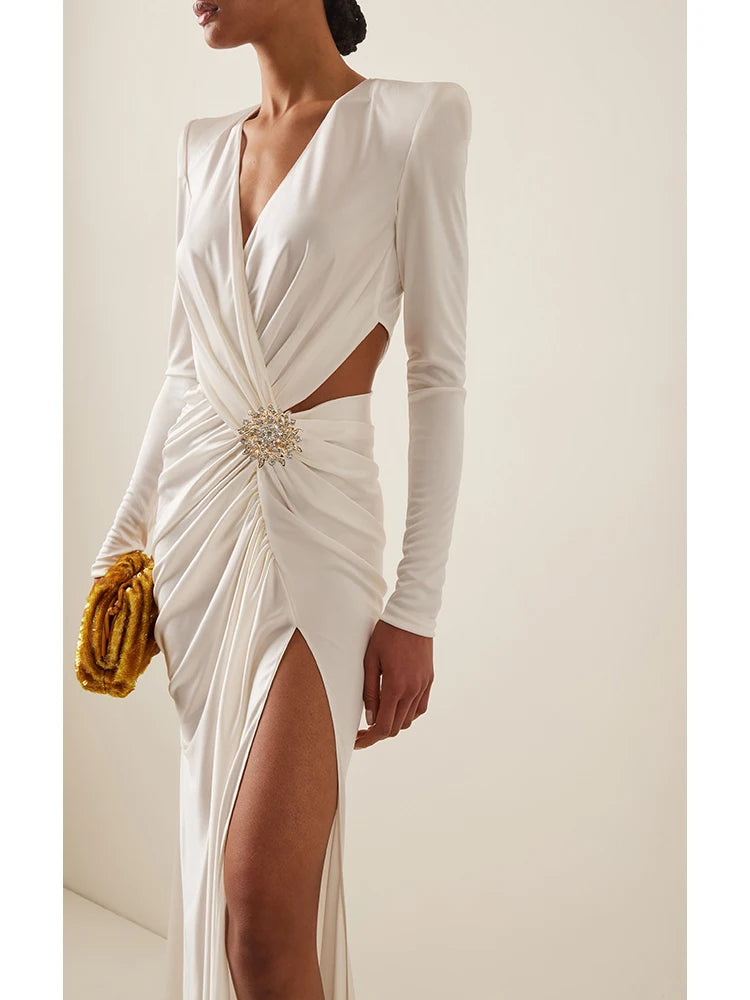 White evening gown with long sleeves and a cutout design, worn by a model against a neutral background.