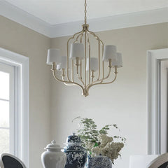 A retro-style chandelier with an iron frame, hanging in a spacious living room with high ceilings.