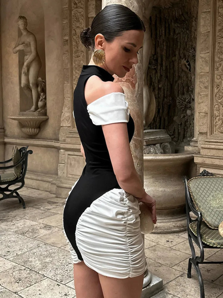 Woman in a black and white outfit standing in an outdoor setting with classical architecture.