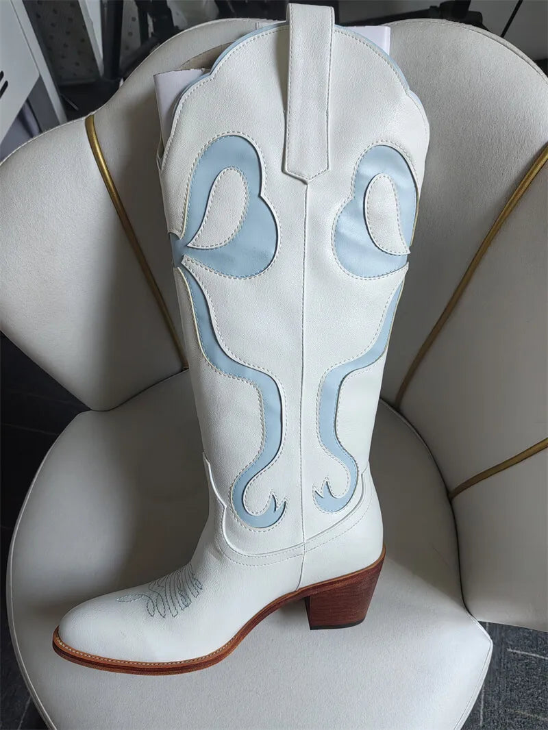 White cowboy boot with blue designs on a white chair.