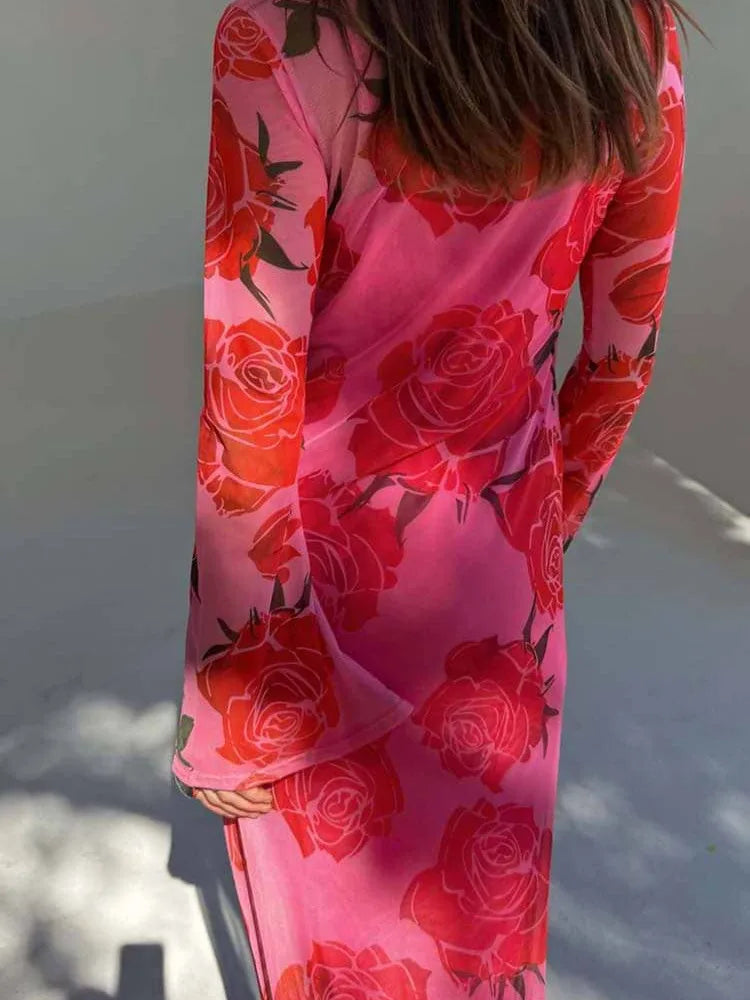 Person wearing a pink dress with red floral patterns in a snowy landscape