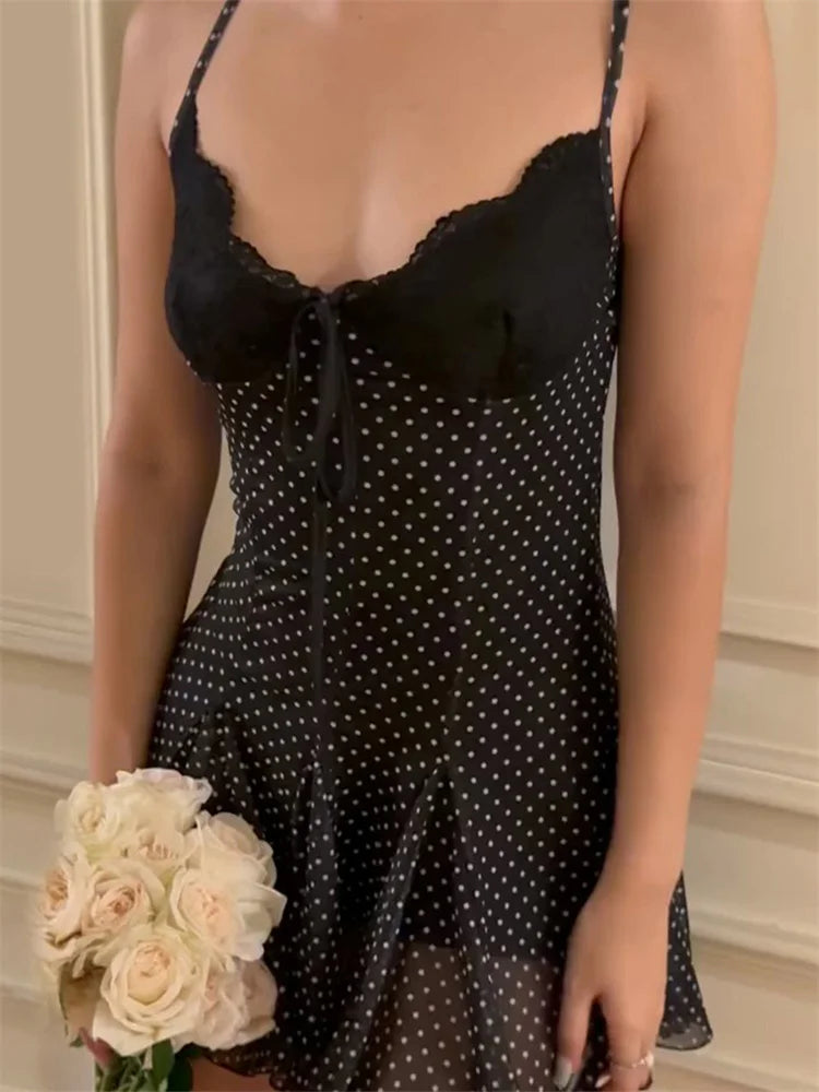 Woman wearing a black polka dot dress holding flowers indoors.