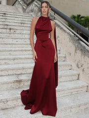 Woman in a burgundy evening gown standing on stone steps.