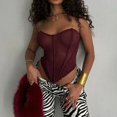 Woman wearing a burgundy bodysuit and zebra print pants against a plain background