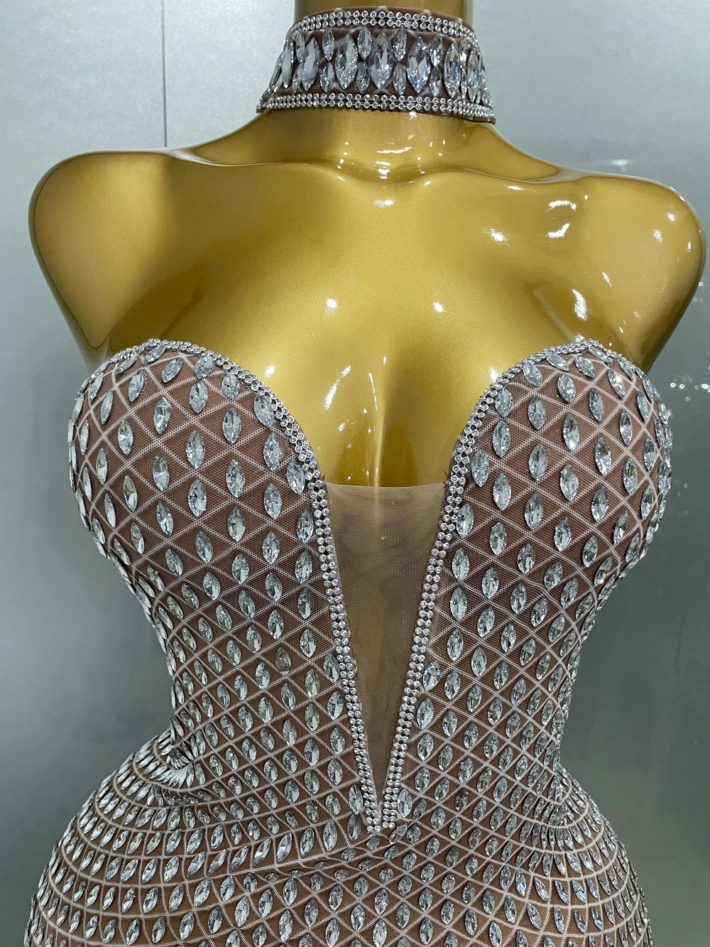 Mannequin wearing a sparkling, intricately designed top with a neutral background