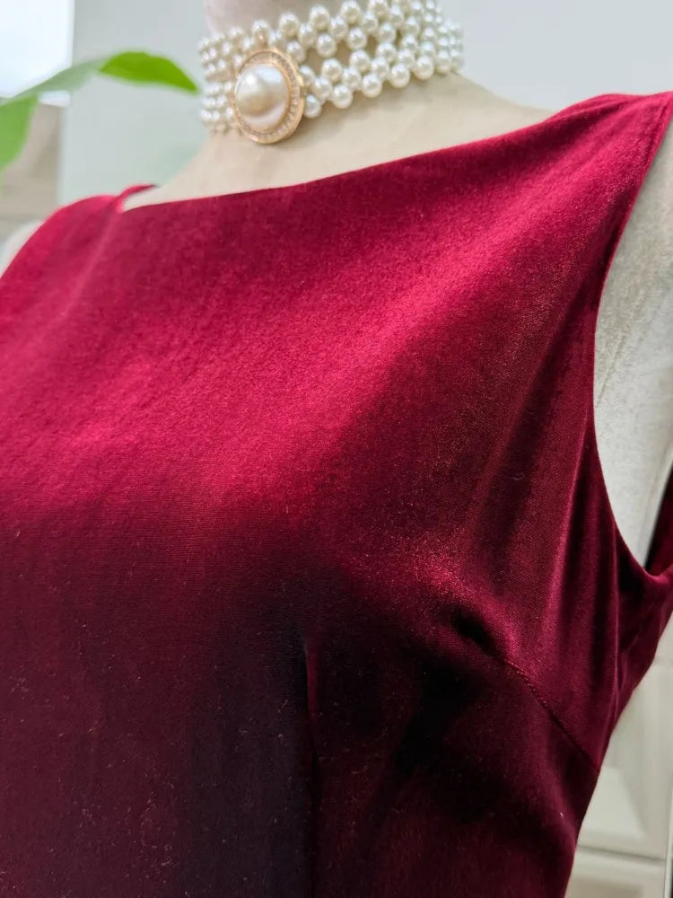 Close-up of a burgundy top with a pearl necklace on a mannequin.