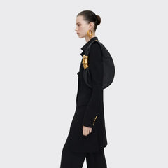 Model carrying a black grained leather half moon shoulder bag with sculpted gold face hardware