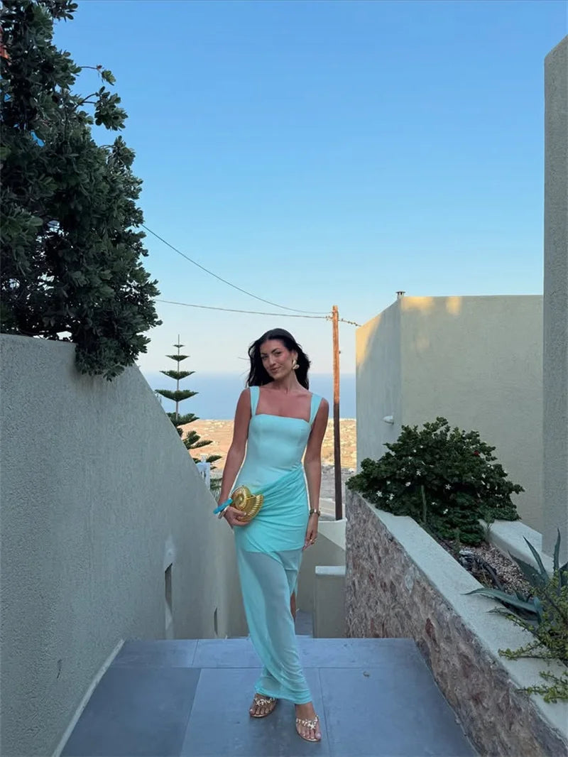 Woman in a light blue dress standing on a pathway with a scenic background