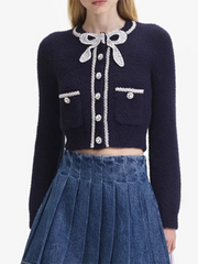 Navy blue cardigan with white lace details worn by a person on a white background