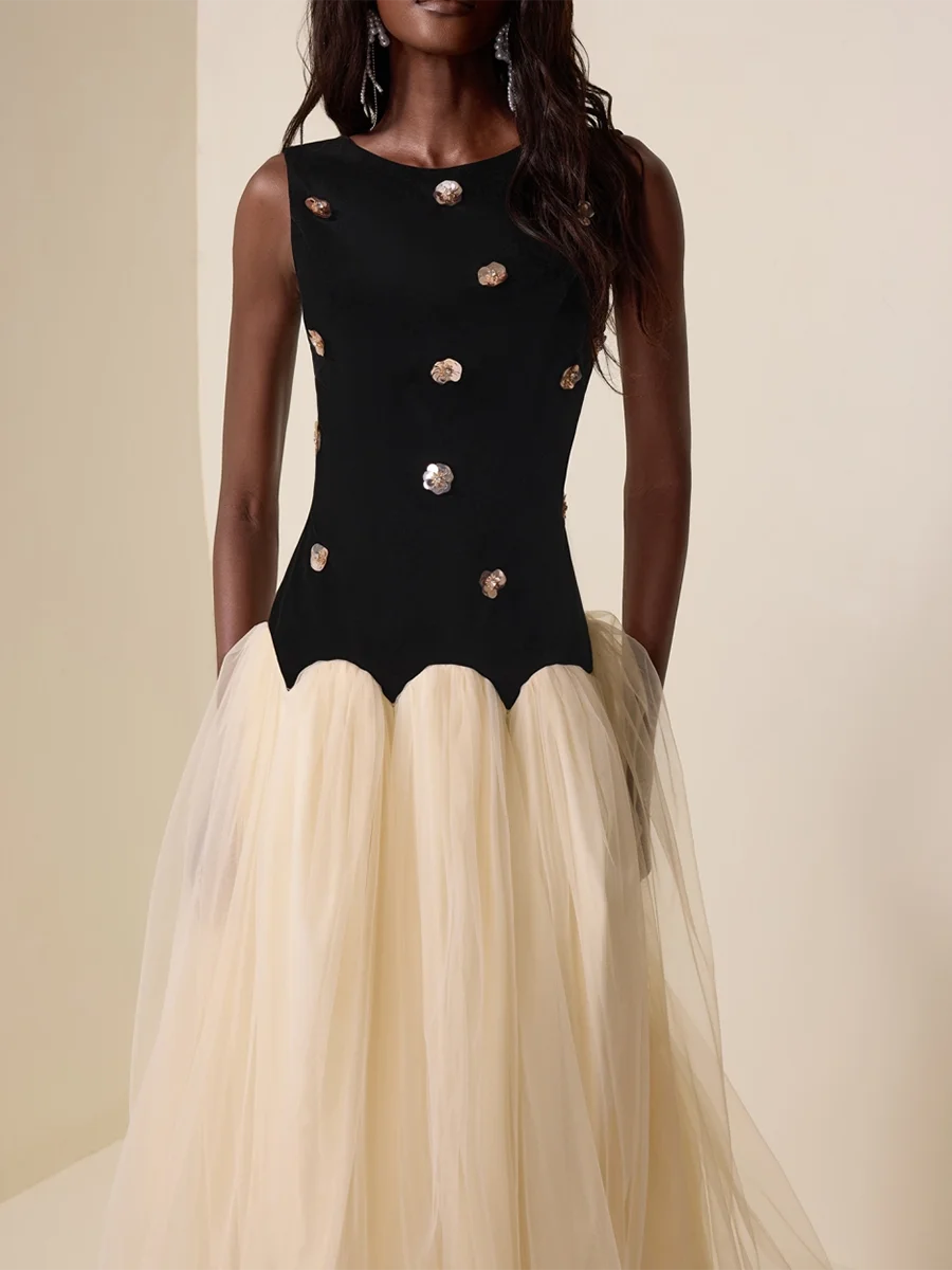 Black bodice with gold buttons and beige skirt worn by a model against a neutral background