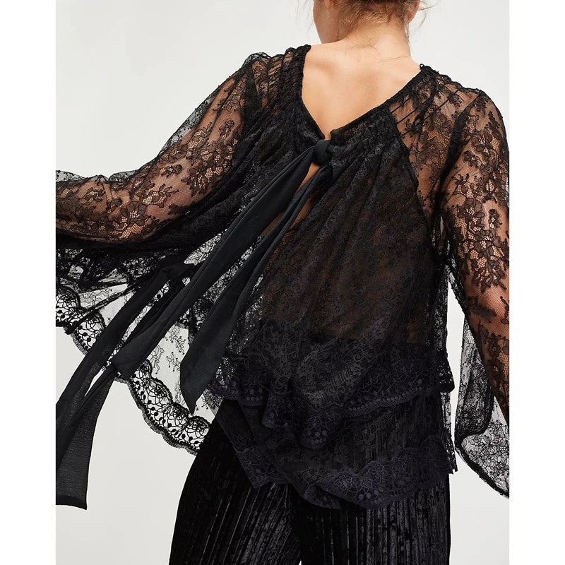 Black lace top with long sleeves and a tie detail on a white background