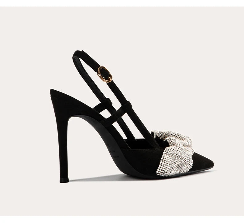 Black high-heeled sandal with a decorative bow on a light gray background