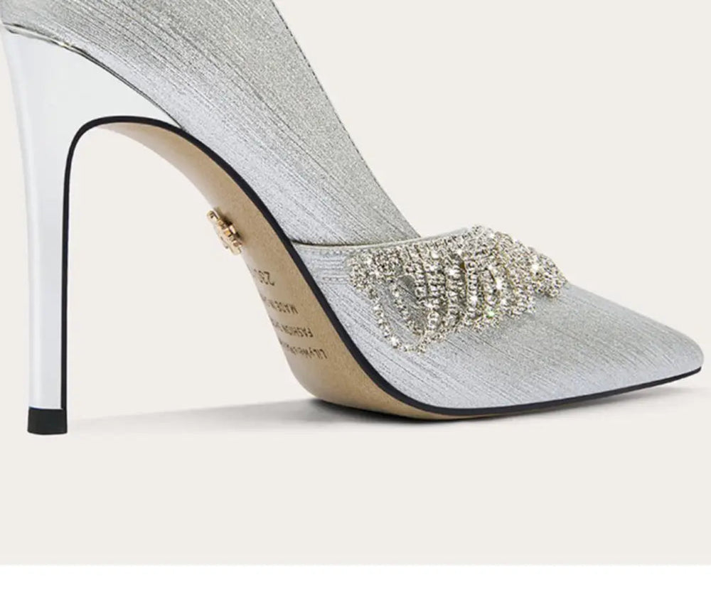 Silver high-heeled shoe with embellishments on a white background