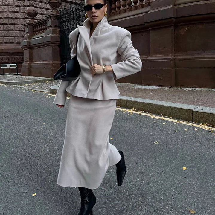 Woman in a gray outfit walking on a street.
