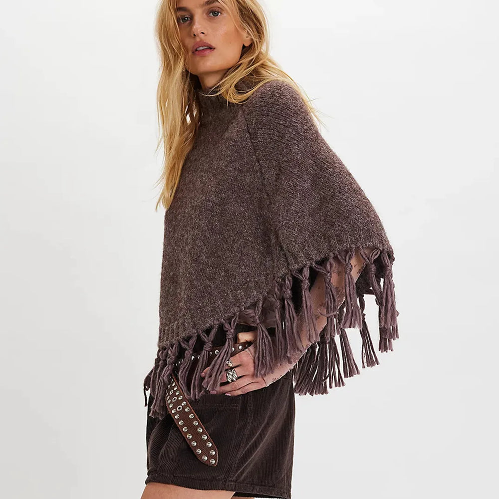 Woman wearing a brown poncho with fringe on a white background