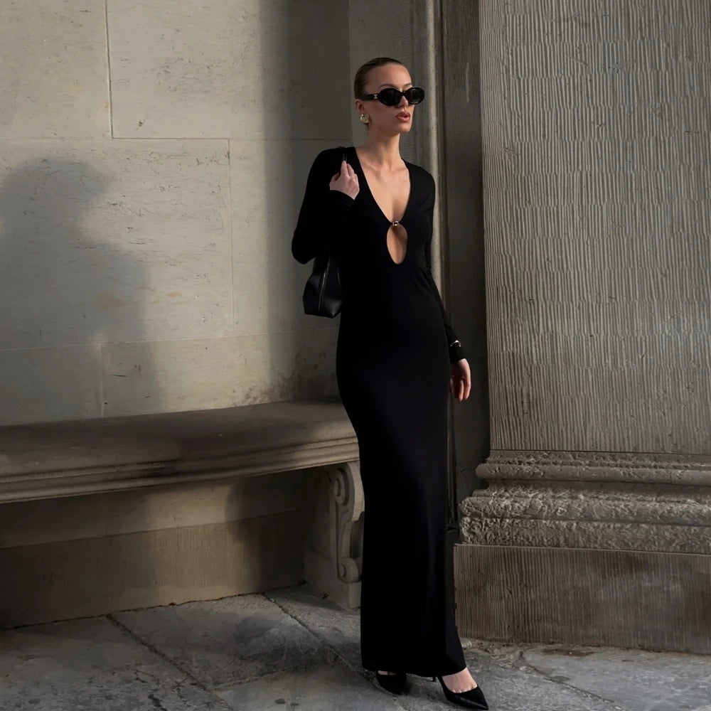 Woman in a black dress standing against a stone wall