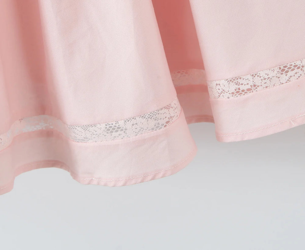 Close-up of a pink curtain with lace trim on a light gray background