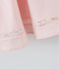 Close-up of a pink curtain with lace trim on a light gray background