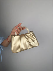 Hand holding a pink gathered clutch bag with a pearl handle