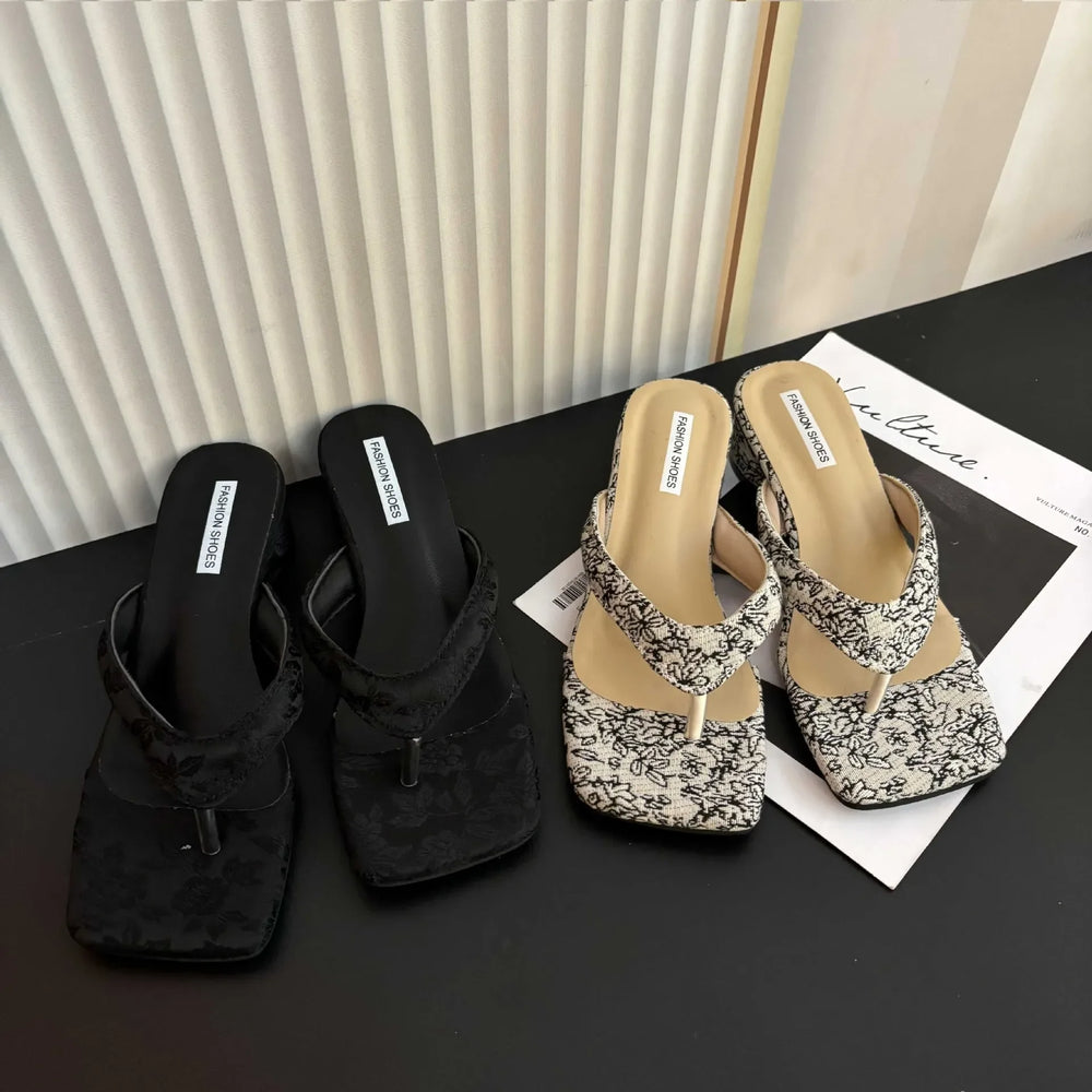 Black and patterned sandals on a black surface with a white background