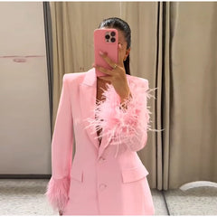 Person wearing a pink outfit with feather details, holding a pink phone.