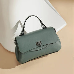 Green handbag with a metallic clasp on a beige background