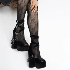 Close-up of black velvet platform sandals with chunky block heel and decorative charms.