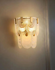 Decorative wall light fixture with glass panels on a neutral wall.